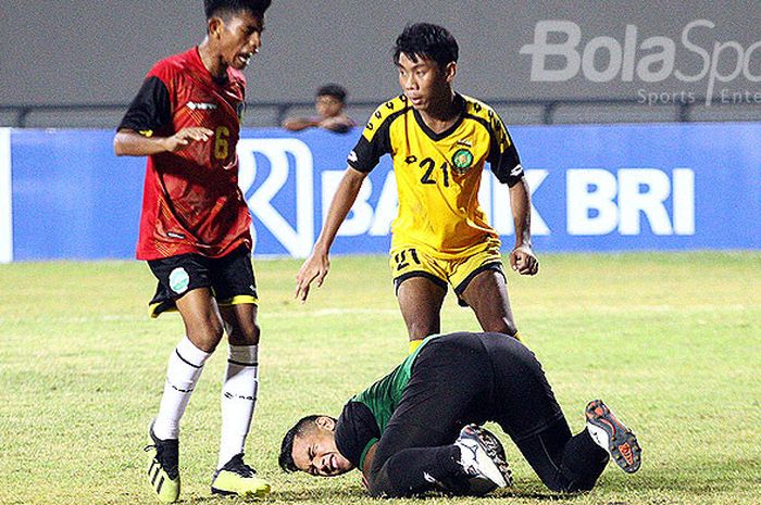 Penjaga gawang Brunei Darussalam U19, AK Muhd. Amirul Hakim menyelamatkan bola dari pemain Timor Leste U-19, Jhon Frith Liu Ornai De Olivera (merah) pada laga Grup B di Stadion Gelora Joko Samudro Gresik, Rabu (4/7/2018).