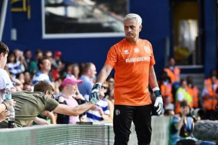 Jose Mourinho berjabat tangan dengan suporter di belakang gawang yang sedang ia jaga.