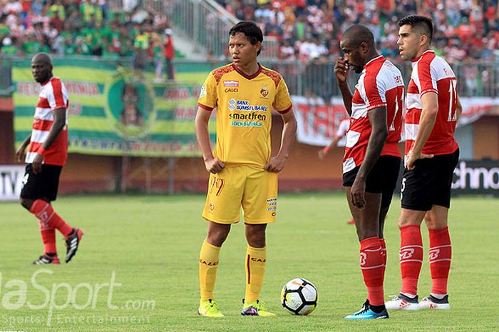 Pemain Madura United, Greg Nwokolo (tengah) dan Fabiano Beltrame (kanan), bersiap melakukan tendangan bebas sementara gelandang Sriwijaya FC, Adam Alis, mengatur pagar betis saat kedua tim bentrok di pekan ketiga Liga 1 di Stadion Gelora Ratu Pamellingan Pamekasan, Jawa Timur Sabtu (07/04/2018) sore.