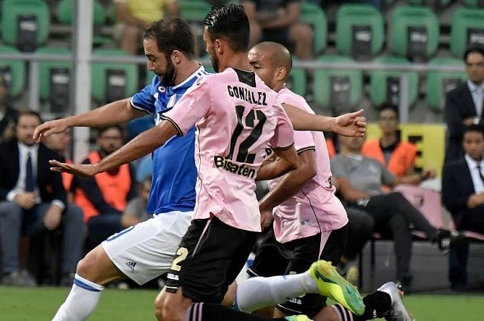 Penyerang Juventus, Gonzalo Higuain (biru), ditempel ketat oleh dua pemain Palermo dalam laga Serie A di Stadion Renzo Barbera, Palermo, 24 September 2016.