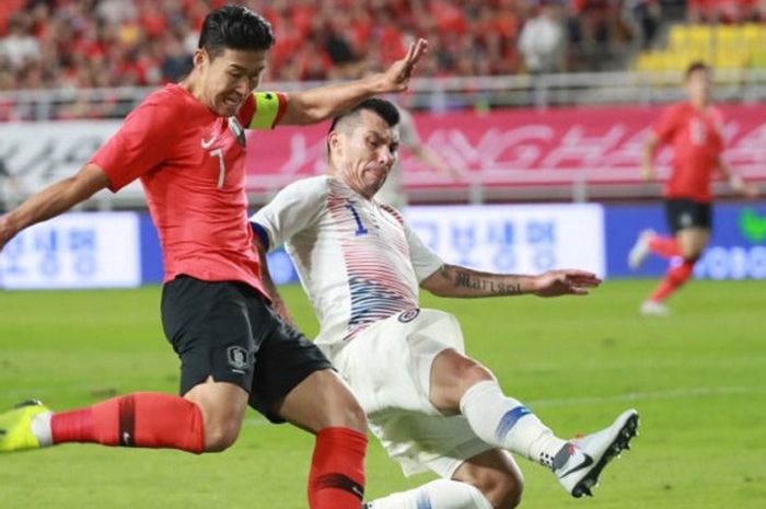 Pemain andalan Korea Selatan, Son Heung-min (kiri), berusaha menendang bola saat dihadang pemain Chile Gary Medel ketika keduanya melakoni laga persahabatan di Stadion Suwon, Suwon, Spanyol pada 11 September 2018.