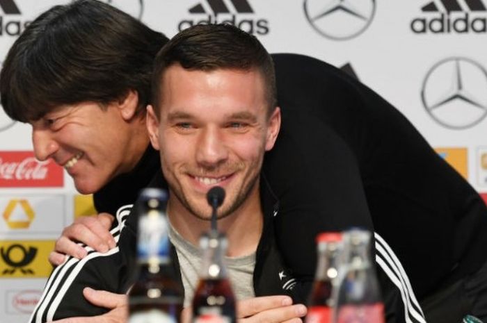 Pelatih Jerman, Joachim Loew (belakang), memeluk Lukas Podolski pada konferensi pers menjelang laga uji coba kontra Inggris di Dortmund, Rabu (22/3/2017). 