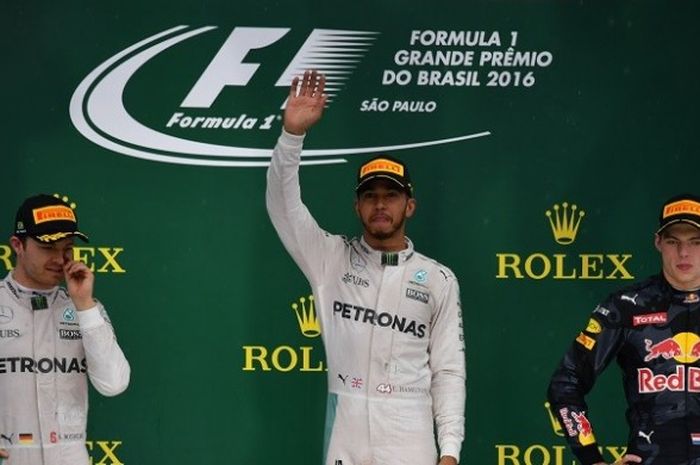 Pebalap Mercedes, Lewis Hamilton, melambaikan tangan di atas podium setelah finis di urutan pertama pada GP Brasil yang berlangsung di Autódromo José Carlos Pace, Sao Paulo, Minggu (13/11/2016). Finis kedua, Nico Rosberg (Mercedes-kiri) dan finis ketiga Max Verstappen (Red Bull Racing-kanan).