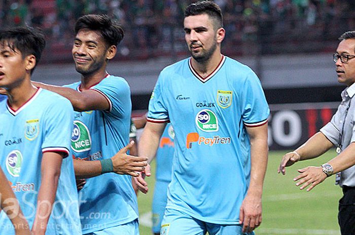   Pelatih Persela Lamongan, Aji Santoso bersama pemainnya bersalaman dengan tim Persebaya Surabaya laga di Gelora Bung Tomo Surabaya, Minggu (5/8/2018).  