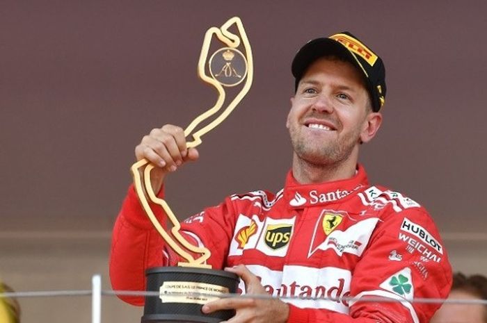 Pebalap Ferrari asal Jerman, Sebastian Vettel, berpose dengan trogi yang didapat setelah finis di urutan pertama pada GP Monaco yang berlangsung di sirkuit jalan raya Monaco, Minggu (28/5/2017).