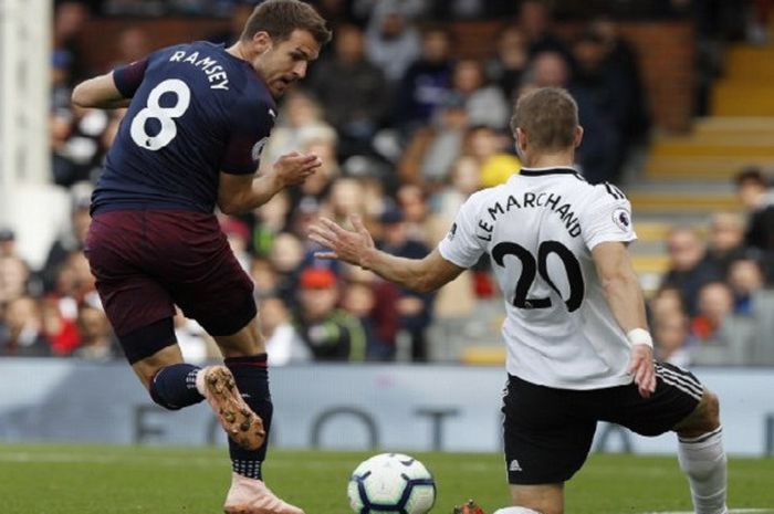 Gelandang Arsenal, Aaron Ramsey, melakukan sentuhan akhir dengan tendangan backheel yang coba diantisipasi pemain Fulham, Maxime Le Marchand, dalam laga Liga Inggris yang berlangsung di Stadion Craven Cottage, Minggu (7/10/2018) malam WIB.