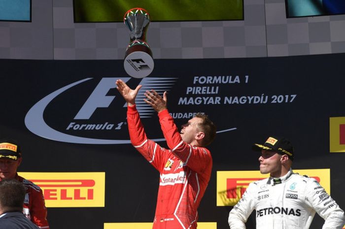 Pebalap Ferrari asal Jerman, Sebastian Vettel (tengah), melempar trofinya ke udara sebagai bentuk selebrasi atas kemenangan pada GP Hungaria di Hungaroring, Budapest, Minggu (30/7/2017).