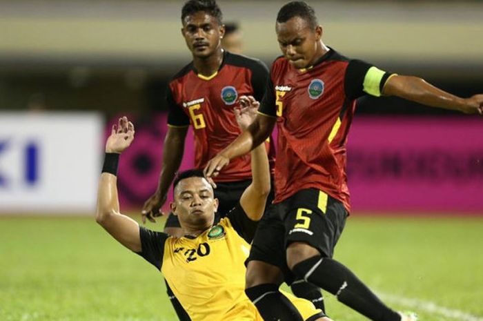 Striker Brunei Darussalam, Adi Said (tengah) berusaha merebut bola dari kapten Timor Leste, Jorge Sabas Victor (kanan) pada babak kualifikasi leg kedua Piala AFF 2018 di Stadion Sultan Hassanal Bolkiah (9/8/2018).