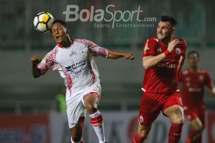 Bek Persipura Jayapuyra, Yohanis Tjoe, menyundul bola dalam kawalan bomber Persija Jakarta, Marko Simic, dalam pertandingan Liga 1 di Stadion Pakansari, Cibinong, Jumat (25/5/2018). 
