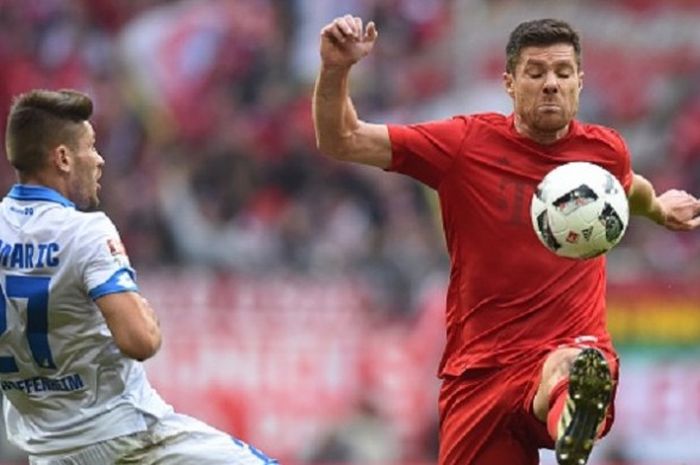 Gelandang FC Bayern, Xabi Alonso, memenangi perebutan bola dengan pemain Hoffenheim, Andrej Kramaric, saat kedua tim beradu di Allianz Arena, Sabtu (5/11/2016). 