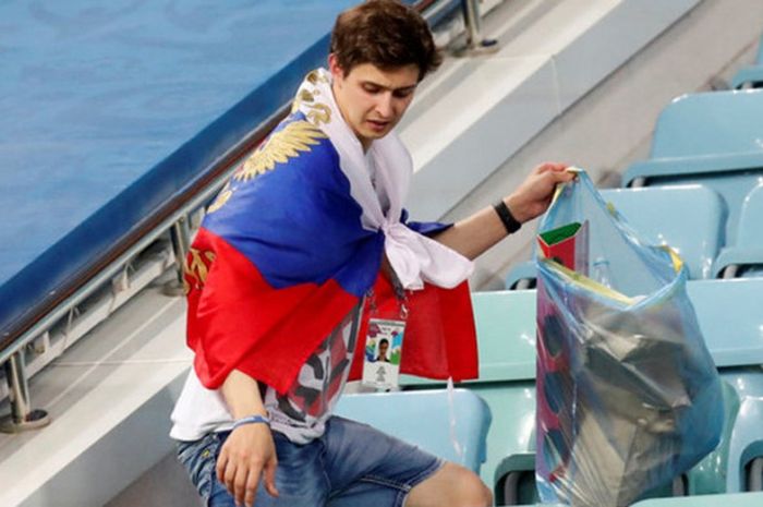 Fan Rusia melakukan aksi bersih-bersih stadion.