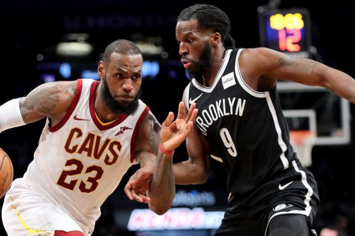 Pebasket megabintang Cleveland Cavaliers, LeBron James (jersey putih, #23), berupaya melawati pemain Brooklyn Nets, DeMarre Carroll, saat melakoni laga musim reguler NBA 2017-2018 di Barclays Center, Brooklyn, New York City, Amerika Serikat, 25 Maret 2018.