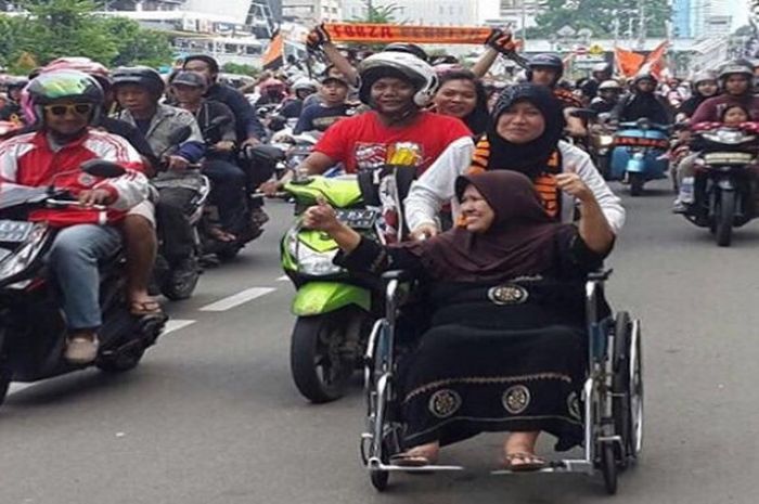 Seorang wanita tetap semangat ikut konvoi meski harus memakai kursi roda.