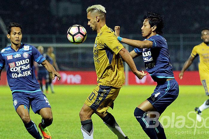 Gelandang Persib Bandung, Raphael Maitimo, berupaya menguasai bola dibayangi dua pemain Arema FC, Sy
