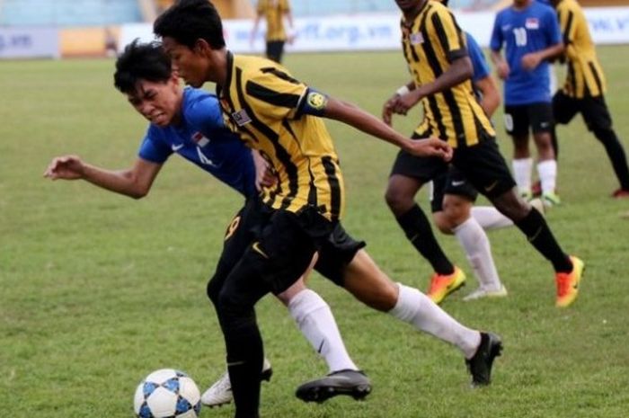 Pemain Malaysia U-19 (kuning) berebut bola dengan pilar Singapura U-19 di Stadion Hang Day, Hanoi, Kamis (15/9/2016). 