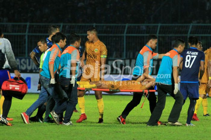 Pemain Bhayangkara FC, TM Ichsan ditandu keluar lapangan saat laga kontra Arema FC di Stadion Kanjuruhan, Kab Malang, Selasa (30/1/2018).