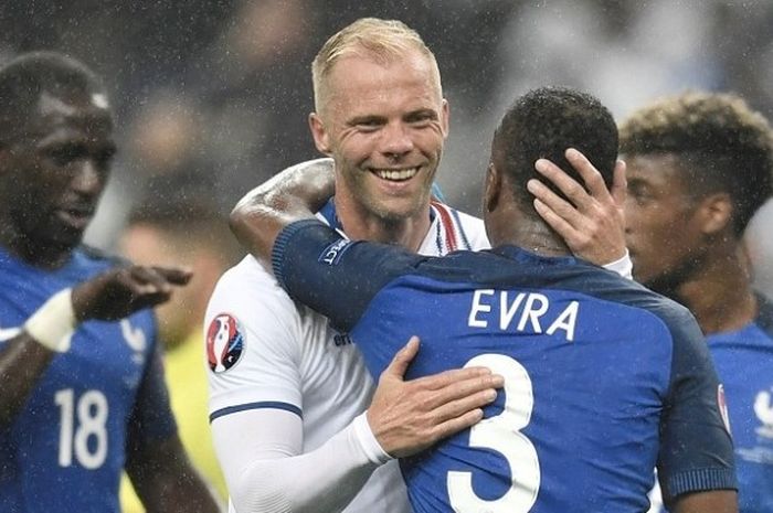 Pemain tim nasional Eslandia, Eidur Gudjohnsen, memeluk pemain Prancis, Patrice Evra, seusai laga perempat final Piala Eropa 2016 di Stade de France, 3 Juli 2016.