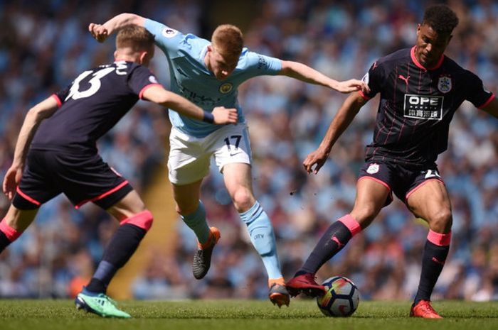  Gelandang Manchester City, Kevin De Bruyne tengah berebut bola dengan dua pemain Huddersfield Town pada laga pekan ke-37 Liga Inggris di Stadion Etihad, Minggu (6/5/2018) malam WIB. 