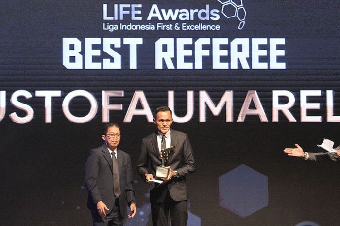 Wasit Mustofa Umarella (tengah) menerima trofi wasit terbaik Liga 1 musim 2017 pada malam penghargaan di Hotel Mulia, Senayan, Jakarta, Jumat (22/12/2017).