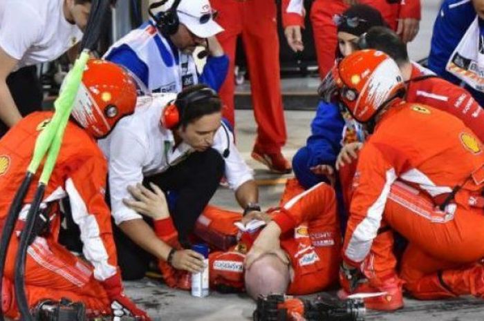 Kru Ferrari, Francesco Cigorini, menahan kesakitan setelah tertabrak ban belakang milik pebalap mereka, Kimi Raikkonen, pada balapan Formula 1 GP Bahrain di Sirkuit Sakhir, Bahrain, Minggu (8/4/2018). 