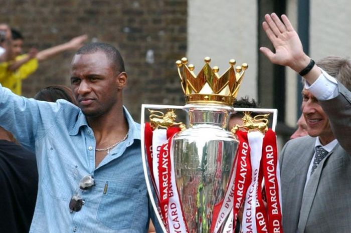 Pelatih Arsenal, Arsene Wenger (kanan), melambaikan tangan bersama Patrick Vieira saat tur dengan bus atap terbuka pada 16 Mei 2004 untuk merayakan kemenangan Arsenal pada Liga Inggris 2003-2004.