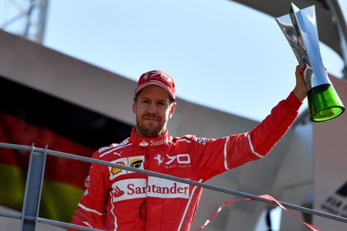 Pebalap Ferrari, Sebastian Vettel, mengangkat trofi yang diraihnya setelah finis di urutan ketiga pada GP Italia di Autodromo Nazionale, Monza, Minggu (3/9/2017).