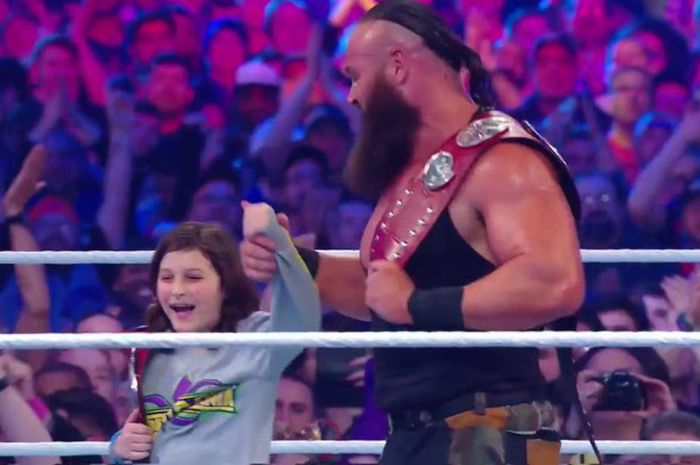 Braun Strowman (kanan) dan seorang anak kecil bernama Nicholas (kiri) saat berselebrasi usai memenangkan WWE Raw Tag Team Championship pada ajang WrestleMania 34, Minggu (8/4/2018).