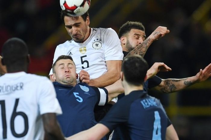 Bek Inggris, Michael Keane, menyaksikan rekan setimnya, Gary Cahill (bawah), berduel dengan palang pintu Jerman, Mats Hummels (atas), dalam partai uji coba di Stadion Signal Iduna Park, Dortmund, Jerman, pada 22 Maret 2017.