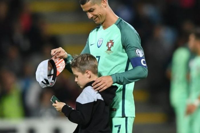 Megabintang timnas Portugal, Cristiano Ronaldo, menyambut fan cilik dalam pertandingan Kualfikasi Piala Dunia 2018 kontra Latvia di Stadion Skonto, Jumat (9/6/2017).