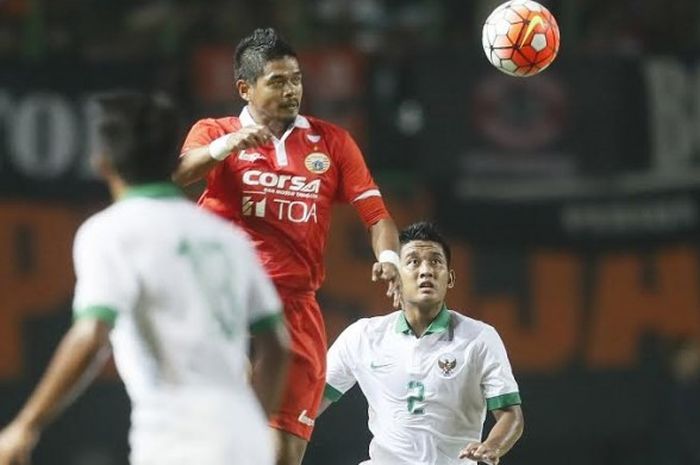 Penyerang Persija, Bambang Pamungkas melompat melakukan sundulan dan bek timnas U-22, I Putu Gede Juni Antara melihat terpana pada uji coba di Stadion Patriot, Kota Bekasi, Rabu (5/4/2017) malam.