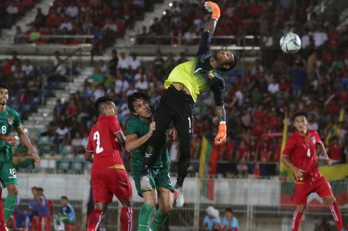 Kiper timnas Myanmar, Kyaw Zin Htet terpelanting saat mencoba mengamankan gawangnya dari serangan pemain timnas Bolovia pada uji coba di Stadion Thuwunna, Yangon, 13 Oktober 2018. 