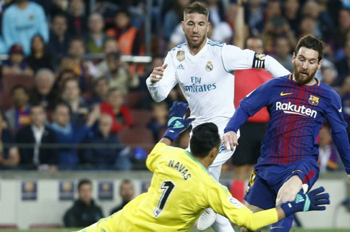   Bek Real Madrid, Sergio Ramos (tengah) mencoba mengejar Lionel Messi dalam pertandingan La Liga Spanyol 2017-2018 kontra Barcelona di Stadion Camp Nou, Barcelona, Spanyol, pada Minggu (6/5/2018).        