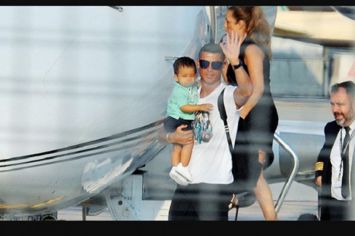 Cristiano Ronaldo ketika tiba di Kota Turin, Minggu (29/7/2018), mengenakan jet pribadi, dia tampak menggendong putra bungsunya.
