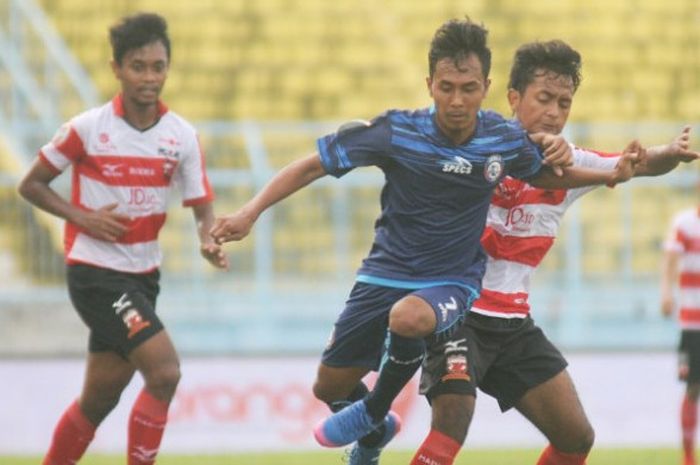 Pemain Arema FC U-19 Heru Wicaksono coba melewati pemain pemain Madura United dalam laga di Stadion Kanjuruhan,  Kabupaten Malang pada Minggu sore (30/7/2017)