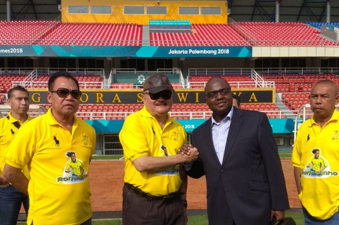 Mantan Gubernur Sumsel, Alex Noerdin (bertopi) bersalaman dengan Oliver Marquee dari manajemen Ronaldinho saat mengunjungi Stadion Gelora Sriwijaya, Jakabaring, Palembang pada Sabtu (8/12/2018). 