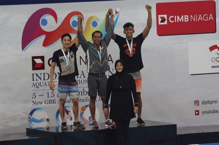 Perenang putra Indonesia, I Gede Siman Sudartawa (tengah), berpose di atas podium sebagai juara pada nomor 50 meter gaya punggung di Stadion Akuatik, Senayan, Jakarta, Selasa (12/12/2017).