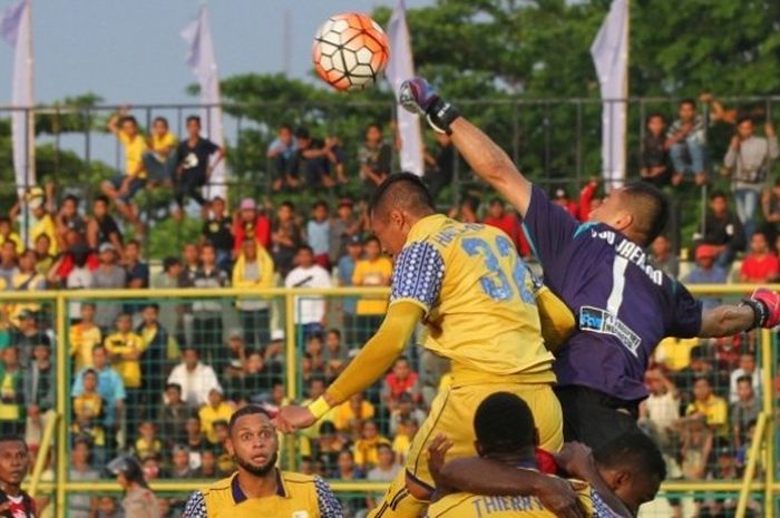 Kiper Persipura, Yoo Jae-hoon berusaha meninju bola saat bek Barito Putera, Hansamu Yama mencoba menyundulnya pada laga di Stadion 17 Mei, Banjarmasin,   Kamis (13/10/2016).