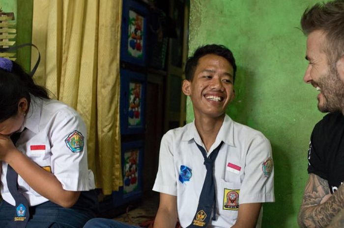 Duta Kehormatan UNICEF David Beckham tertawa bersama Sripun (15) dan temannya, Ego, di rumah nenek Ego di Semarang, Jawa Tengah, Indonesia, 27 Maret 2018. Sripun diunjuk oleh lingkungannya untuk menjadi agen perubahan dan berpartisipasi dalam program anti-bullying yang diinisiasi UNICEF.