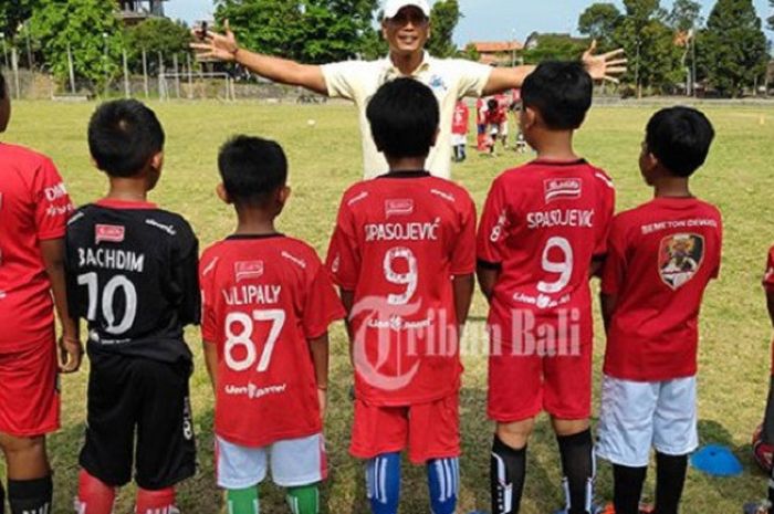 Anak-anak berpose bersama dengan pelatih Mitra Devata Legend sekaligus penyerahan bantuan bola Bali United kepada warga Pejeng, Minggu (14/10/2018) 
