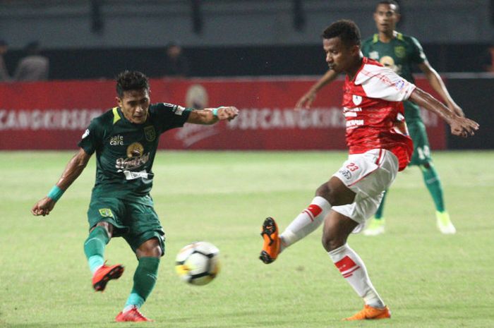 Bola sepakan pemain tengah Persebaya, Sidik Saimima (kiri) coba dihadang penyerang Persipura, Frisca Womsiwor pada lanjutan Liga 1 2018 di Gelora Bung Tomo, Kota Surabaya, 29 Mei 2018. 