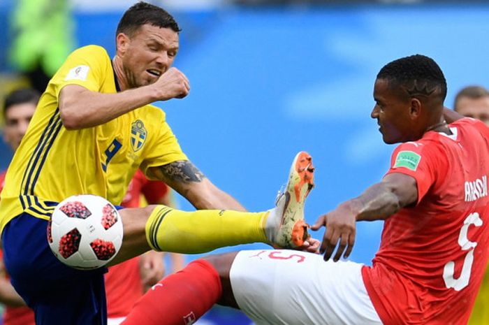 Penyerang timnas Swedia, Marcus Berg (kiri), berduel berebut bola dengan bek Swiss, Manuel Akanji, dalam pertandingan babak 16 besar Piala Dunia 2018 di Stadion Saint-Petersburg, Saint Petersburg, Rusia, pada Rabu (3/7/2018). 