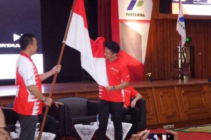 Rio Haryanto mencium bendera Merah Putih yang dipegang Menpora Imam Nahrawi di Gedung Pusat Pertamina, Jakarta, Kamis (18/2/2016).