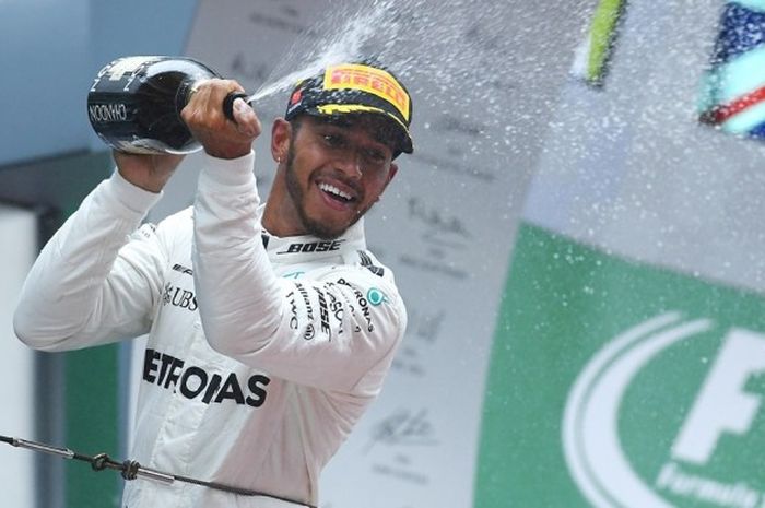 Pebalap Formula 1 (F1) yang membela tim Mercedes, Lewis Hamilton, melakukan selebrasi dengan menyiram rekan-rekan setimnya memakai sampanye. Hamilton tampil sebagai juara GP China yang berlangsung di Sirkuit Internasional Shanghao, Minggu (9/4/2017).