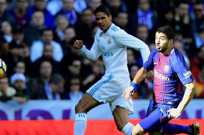 Striker FC Barcelona, Luis Suarez (kanan), berduel dengan bek Real Madrid, Raphael Varane, dalam laga Liga Spanyol di Stadion Santiago Bernabeu, Madrid, pada 23 Desember 2017.