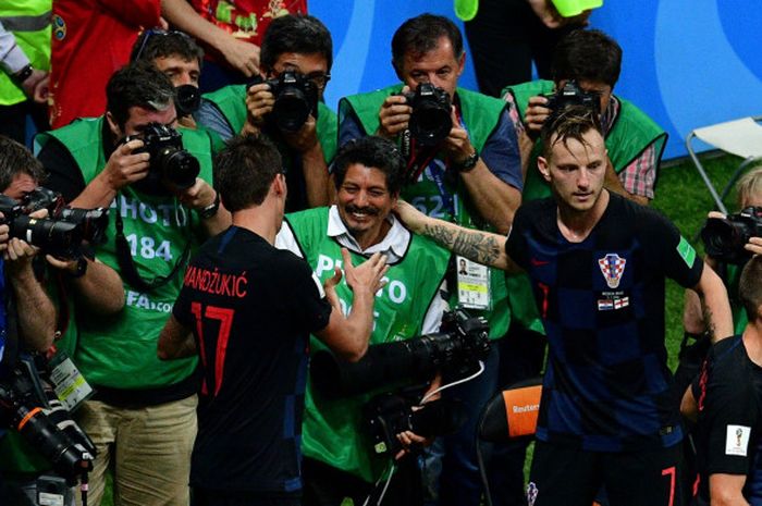 Pemain Kroasia, Mario Mandzukic dan Ivan Rakitic, memastikan bahwa fotografer Yuri Cortez baik-baik saja setelah tertimpa para pemain yang merayakan gol dalam laga semifinal Piala Dunia 2018 melawan Inggris, Rabu (11/7/2018) di Luzhniki Stadium, Moskow.