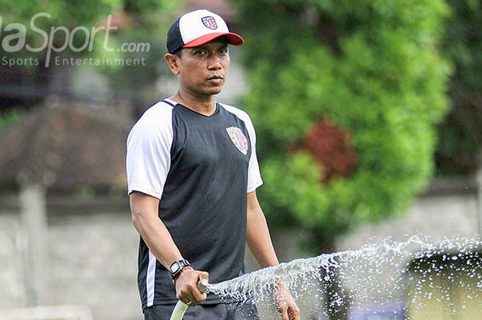 Pelatih Bali United, Widodo Cahyono Putro tengah menyiram rumput lapangan Trisakti, Legian, Senin (26/3/2018) pagi usai memimpin sesi latihan anak asuhnya.