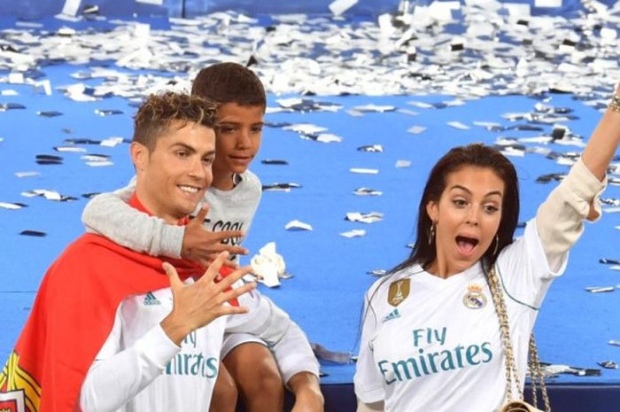  Bintang Real Madrid, Cristiano Ronaldo (kiri), berpose dengan kekasihnya, Georgina Rodriguez, dan putranya, Cristiano Junior, saat merayakan kesuksesan tim menjuarai Liga Champions seusai menekuk Liverpool FC 3-1 dalam final di Stadion NSC Olimpiyskiy, Kiev, Ukraina, pada Sabtu (26/5/2018). 