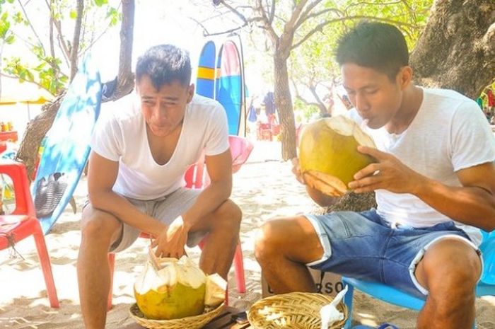Samsul Arif (kiri) dan Purwaka menikmati air kelapa muda di Pantai Kuta pada Sabtu (20/2/2016).