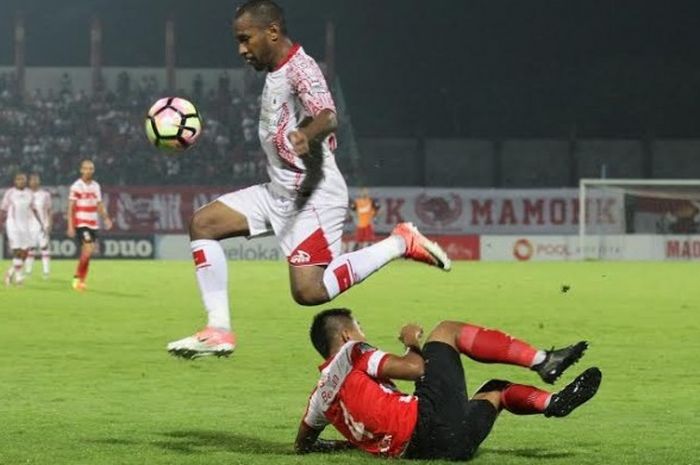Gelandang Persipura, Ian Louis Kabes melompat menghindari pemain bertahan Madura United, Asep Berlian pada pertandingan pekan ke-10 Liga 1 musim 2017 di Stadion Gelora Bangkalan, Rabu (7/6/2017) malam. 