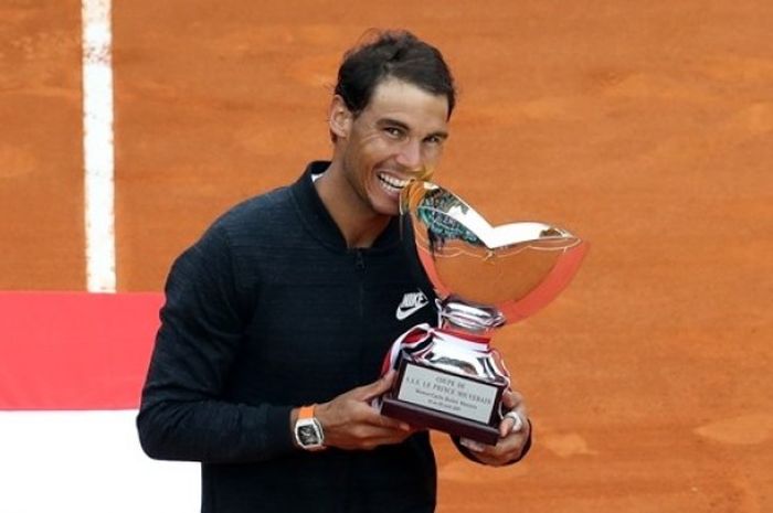 Petenis Spanyol, Rafael Nadal, melakukan selebrasi dengan menggigit trofi juara Monte Carlo Masters. Nadal menjadi kampiun setelah mengalahkan rekan senegara, Albert Ramos-Vinolas, 6-1, 6-3, di Monte Carlo Country Club, Monte Carlo, Monako, Minggu (23/4/2017).
